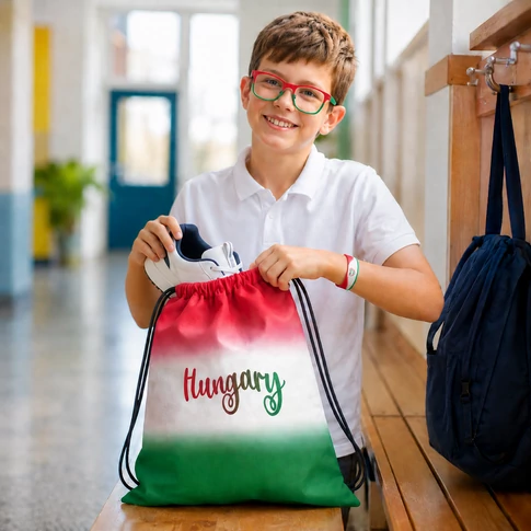 Szurkolói Magyarország tornazsák, Hungary felirattal, piros fehér zöld színű; egy fiú pakolja bele a sportcipőjét.